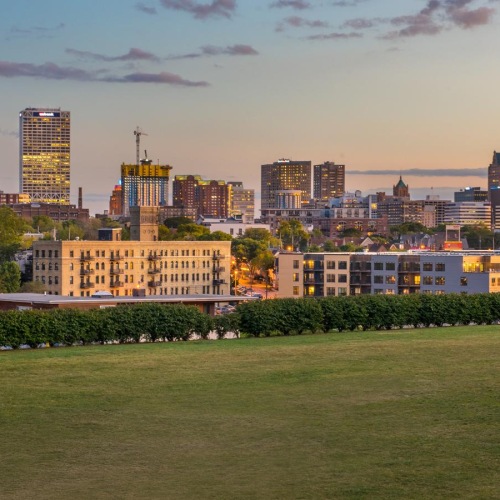 Close to the center of everything a city skyline with a large field in front of it